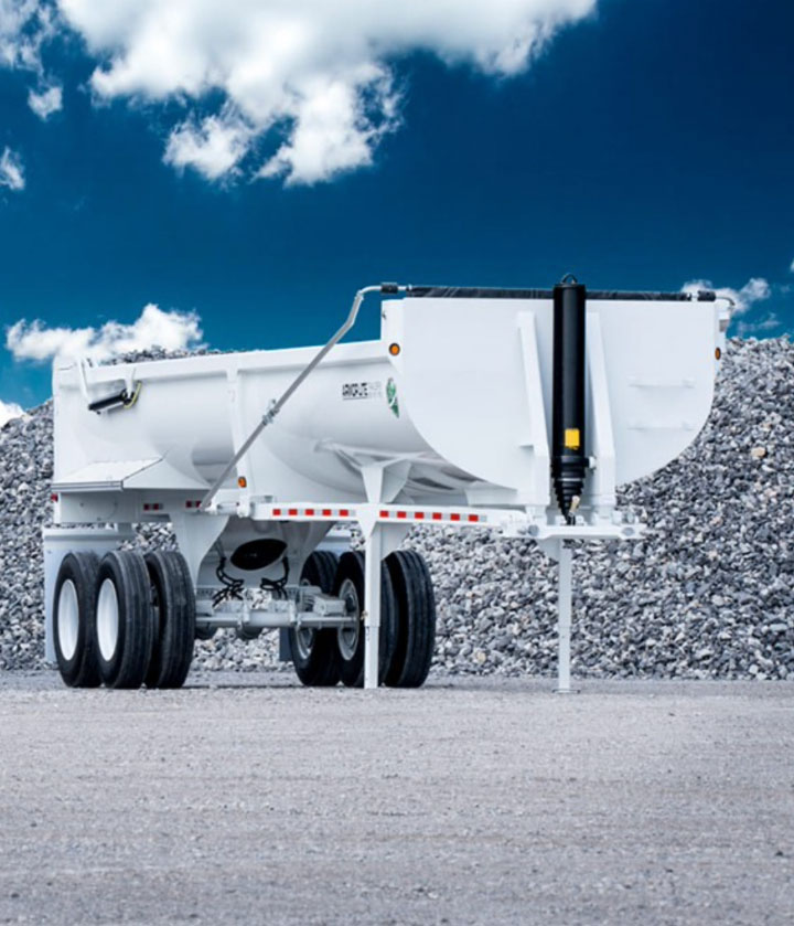 A white half-round dump trailer against a clear blue sky, built by Missouri-based Armor Lite Trailers using Hardox wear plate. 