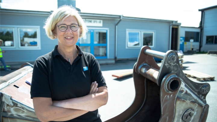 Photo of Götene Ufo’s CEO Birgitta Boström stands next to an excavator bucket.