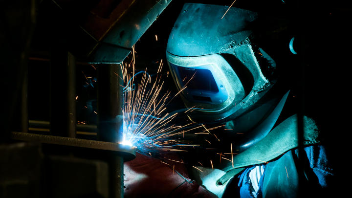 A welder putting the torch to a custom excavator bucket made in Hardox® 500 Tuf