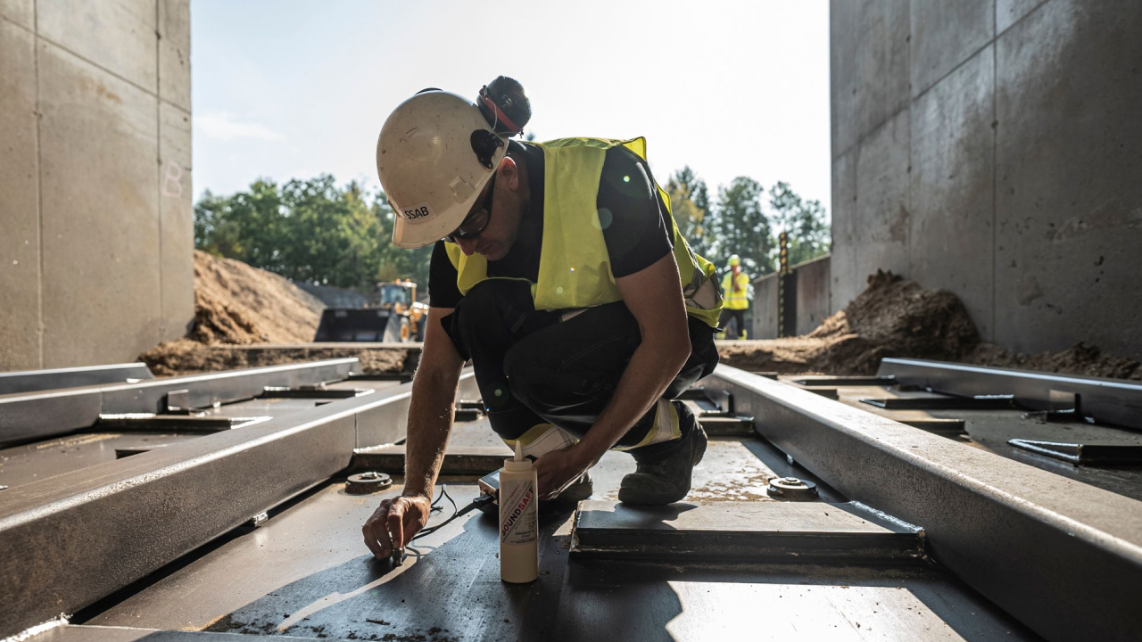 A worker using an ultrasonic measuring device to measure wear on a thick plate of the corrosion-resistant AR steel Hardox® HiAce.