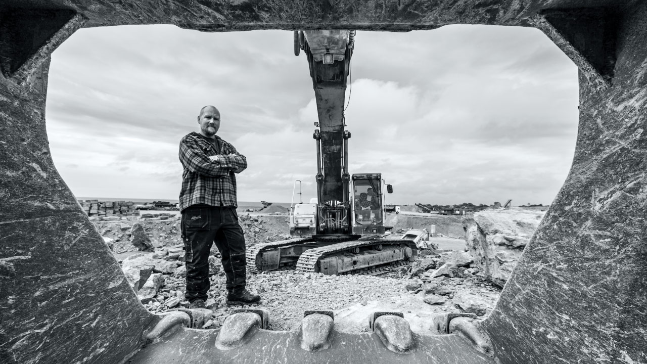 A construction worker on a job site, looking inside a gigantic digging bucket made in Hardox 400 wear plate.