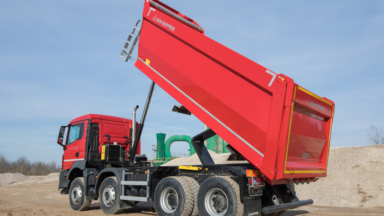 A truck with body made in Hardox® 450 steel, travelling past a job site with a load of abrasive gravel and rocks.