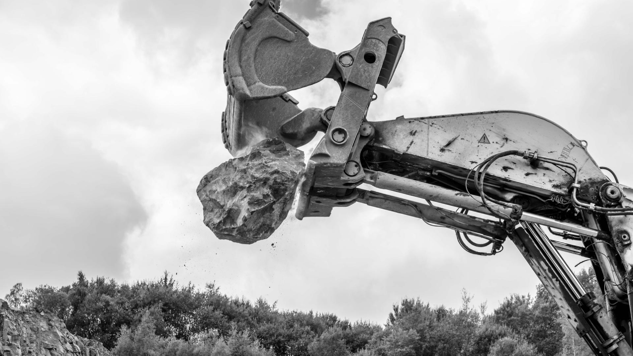 Giant excavator releasing an enormous rock up in the air. The bucket’s edges are made in Hardox® 450 steel.