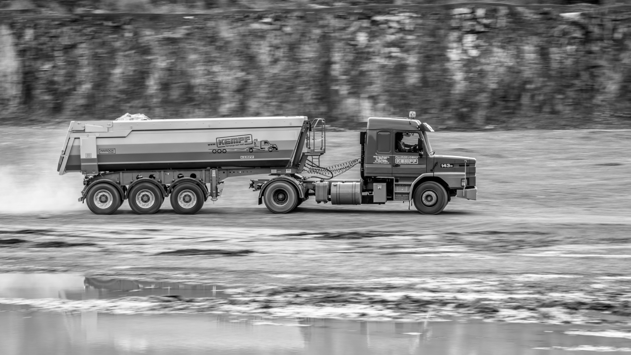 A trailer with Hardox 450 steel in the dump body, on a wet and muddy road.